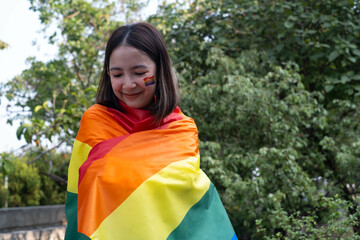 A woman wrapped in a rainbow flag smiles, celebrating diversity and inclusion. The vibrant colors...