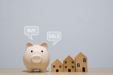 A piggy bank representing savings for real estate investment, with mini wooden houses signifying...