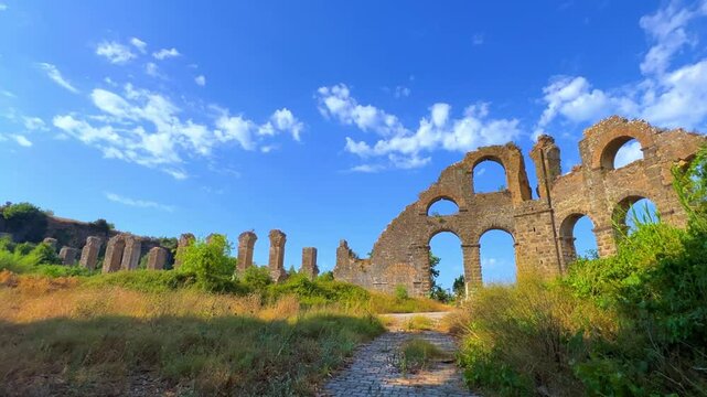 The ancient city of Aspendos. Ruins of aqueducts of Aspendos Acropolis. T&uuml;rkiye. Historical siphon of Aspendos Aqueduct with olive trees, Antalya. 4K