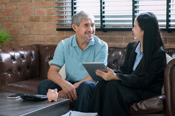 A woman insurance salesperson using tablet computer,presents insurance savings plan to elderly...