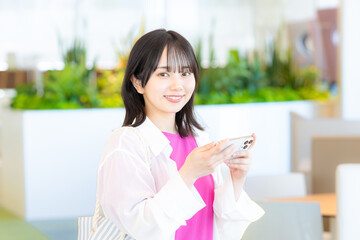 スマホを見る笑顔の女性【撮影協力：学校法人電波学園　東京電子専門学校】
