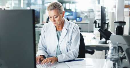 Woman, scientist and typing with research on computer for medical results or discovery at laboratory. Mature, female person or health science worker with technology for scientific report or analysis
