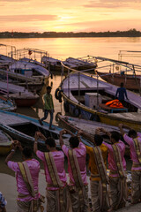 On a beautiful morning in Varanasi, priests offer prayers by the Ganges River as boats rest gently on the water.