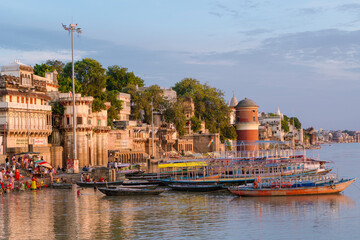 Morning tranquility at Varanasi Ghats, with colorful boats, historic riverside buildings, and...