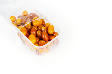 Plastic container of fresh yellow and orange cherry tomatoes isolated on white background. Tomatoes in transparent pack, perfect for grocery, retail, and food market visual content. Copy space