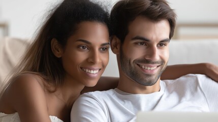A couple smiles warmly, viewing content on a laptop, sharing a moment of togetherness at home.