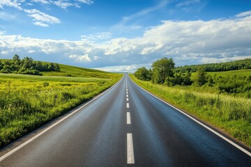 Fototapeta premium Scenic highway stretches through lush green landscape under a bright blue sky