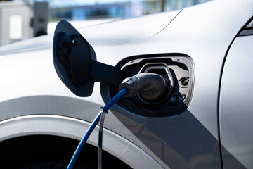 EV or electric car with power cable at charging station. Green energy and eco-power produced from sustainable source to reduce CO2 emissions