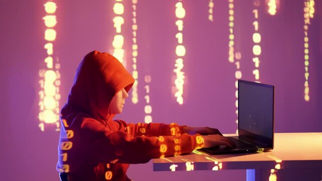 Osoba w kapturze przy laptopie z projekcją kodu binarnego w fioletowo-pomarańczowym świetle