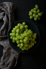 Green grapes on a plate on a dark table