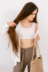 Stylish slim woman with long hair and carrying a woven tote bag