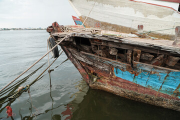 Weathered Fishing Boat Docked in Calm Waters with Rusted Hull and Colorful Details Near Shore