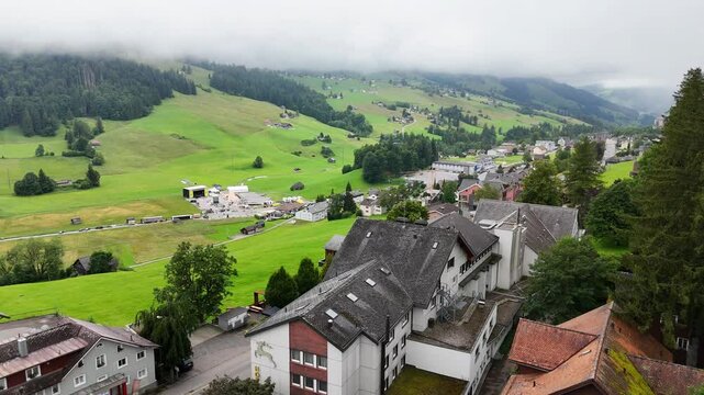 7 juli 2025, Wildhaus-Alt Sint Johann, Switzerland. Drone flight above the village centre of Wildhaus, a charming village near the Alpstein mountain range. Small alpine town centre, houses.