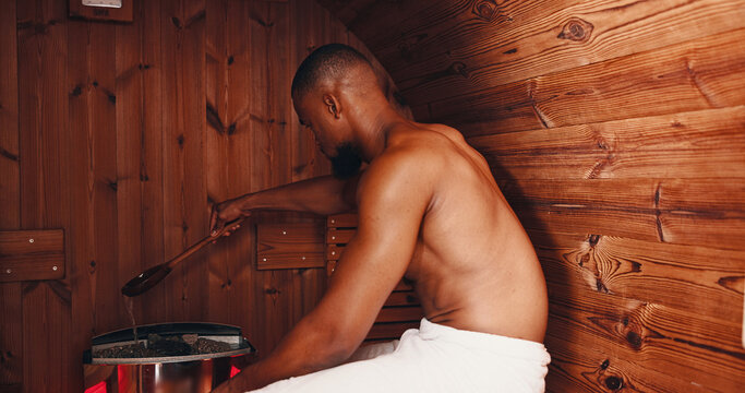 Sauna, fitness and hot stones with black man in gym for muscle recovery, post workout and health in sports center. Detox therapy, athlete cramp and wellness with person in steam room for sweating