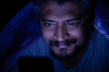 Fototapeta premium Mobile phone addiction, man using mobile phone at night sparing his sleep, social media addiction