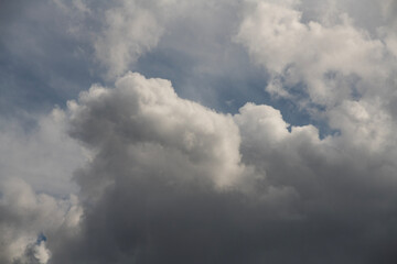 Blue sky with fluffy white close up clouds.