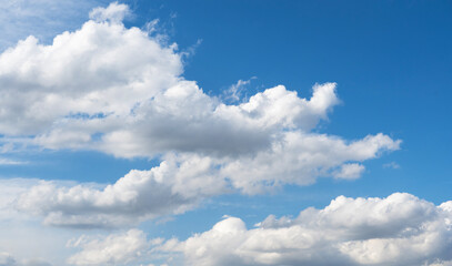 Blue sky with fluffy white close up clouds.