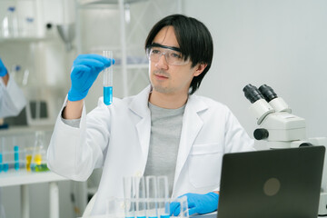 scientist in laboratory carefully examines test tube filled with blue liquid, showcasing researcher...