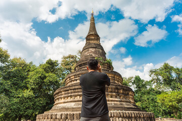 Fototapeta premium Photographer taking pictures of historic brick stupa in Wat Umong famous place at Chiang Mai, Thailand