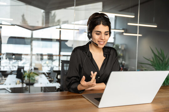 Middle age young female financial specialist holding video call with clients partners online in office. Focused Latin Hispanic woman wearing headset helping as callcenter consult assistant. Copy space