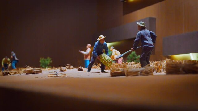Low Angle, Close Up, Miniature model of Asian farmers moving straws in the desert to fixate sand, inside the museum, daytime, Tengger Desert, Ningxia, China, Asia