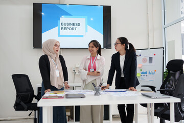 Asian businesswoman in hijab collaborates with colleagues during business meeting in modern office setting