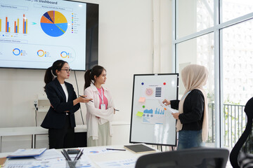 Asian businesswoman presenting data to colleagues in modern office, fostering teamwork and...