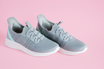Gray women's sneakers close-up on a pink background