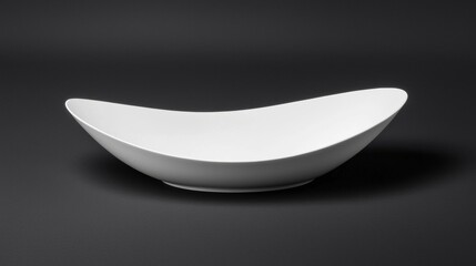 A white bowl with a curved shape sits on a black background.