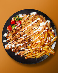 Gyro chicken beef kebab with rice and fries on plate, top view
