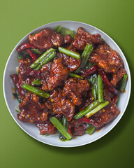 Korean - Thai Stir fried beef in spicy sauce with red chilliand green vegetables, close up view, top view, green background