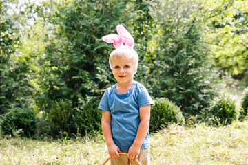 Easter egg hunt.Little boy child kid in bunny ears having fun,picking up eggs in...