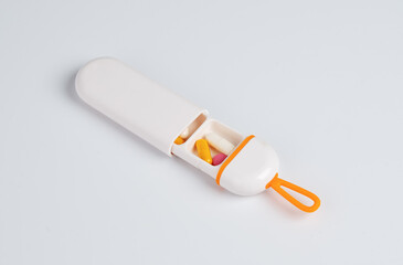 Portable pill case with colorful capsules and tablets inside, isolated on white background, ideal...