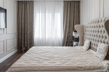 bedroom design with a double bed, large upholstered headboard. the lamp on the bedside table. a...