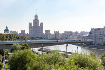 Obraz premium Moscow, Russia - 09.22.2024: Floating bridge by natural landscape park Zaryadye on summer day. People walking on the pedestrian bridge in Moscow. Skyscraper on Kotelnicheskaya embankment on background