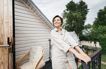 Beautiful young woman on the summer veranda of a country house. She is happy and laughing.