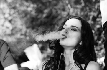 Sexy girl with smartphone smokes hookah