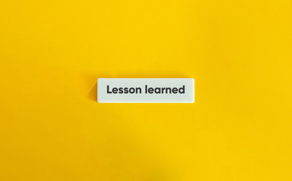 Lesson Learned Phrase. Text on Block Letter Tile on Yellow Background. Minimal Aesthetic.