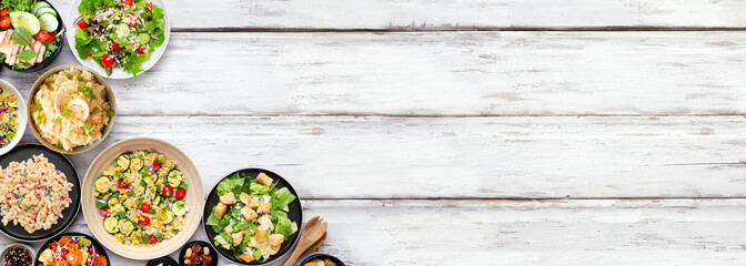Variety of delicious homemade salads. Overhead view corner border on a white wood banner background. Summer food concept. Potato, caesar, pasta and green salads.
