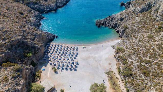 Chalkos beach in Kythira - Scenic beach with sun umbrellas and clear waters nestled between rocky cliffs on a sunny day in a coastal region