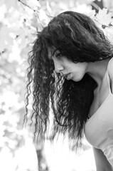 Close-up portrait of a fantastic young model girl posing in the park on a sunny day. Black and white photo.