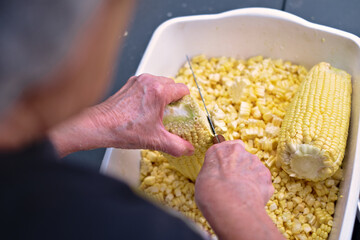Photos of a person slicing or cutting corn on the cob with a knife to prepare cake or humitas