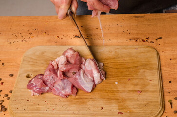 Female hands with a knife in their hand cut fresh meat on a table