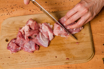 Female hands with a knife in their hand cut fresh meat on a table