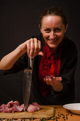 A woman is holding a big steak in her fork and licking her lips.