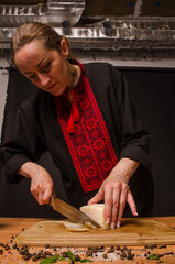 A woman is cutting smoked meat into the kitchen.