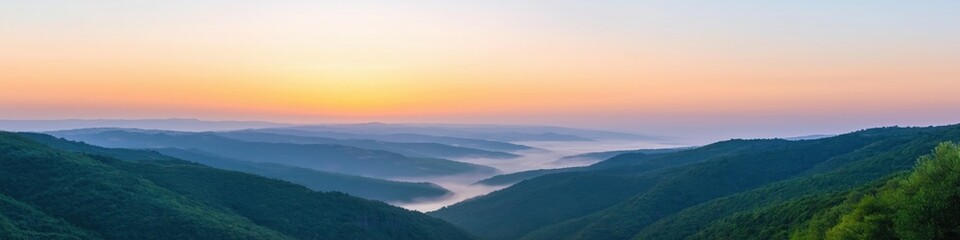 The sky is a beautiful orange color with a few clouds. The mountains are covered in trees and the valley below is foggy