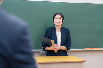 学校で教壇に立って授業をする若い女性教師
