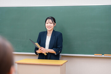 学校で教壇に立って授業をする若い女性教師