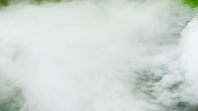 Clip of thick fog, likely caused by water mist. Dai ice  close-up of a rushing stream, possibly a waterfall, a drain, or a fast-flowing river, with fog rising due 